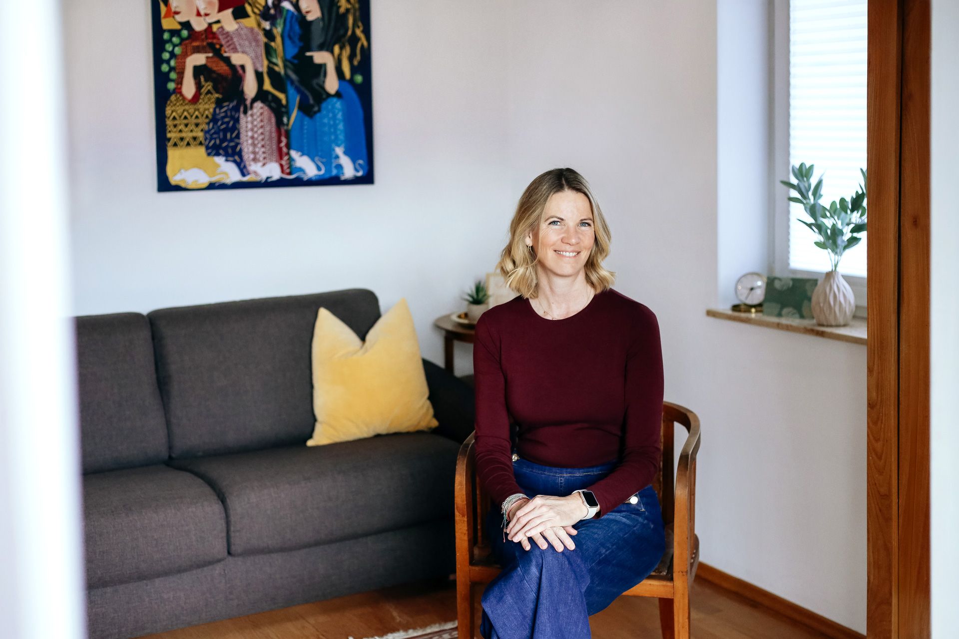 Portrait-Foto von Monika Gatterer, Logopädin und Psychotherapeutin in Puch bei Hallein, Tennengau. Natürliches Porträt – sie sitzt im Psychotherapie-Raum auf einem Holzstuhl.