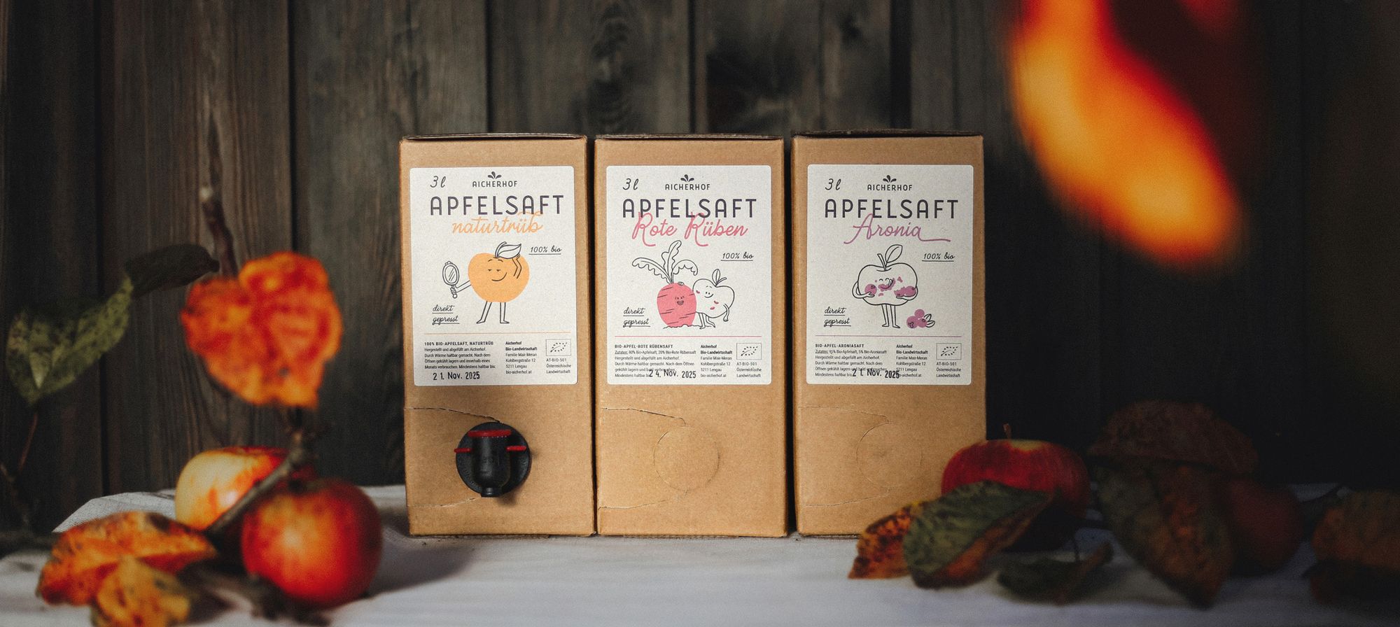 Das neue Packaging der Säfte vom Aicherhof mit Äpfeln im Vordergrund: Apfelsaft naturtrüb und Apfelsaft Rote Rüben und Apfelsaft Aronia