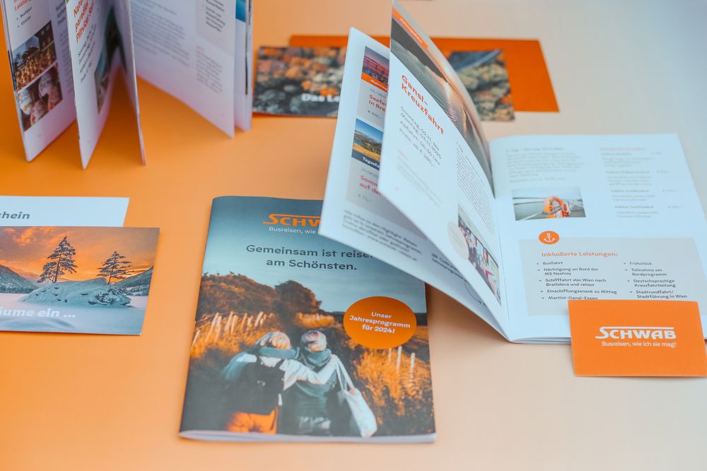 Übersicht an Drucksorten und Werbemittel für Schwab Reisen inkl. Visitenkarten und offenem Reiseprogramm.